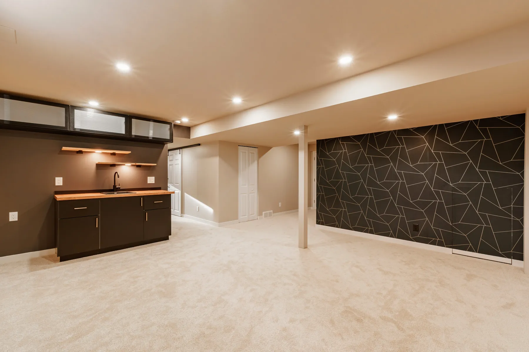 Finished basement with a dark wet bar, wood counter and a geometric feature wall