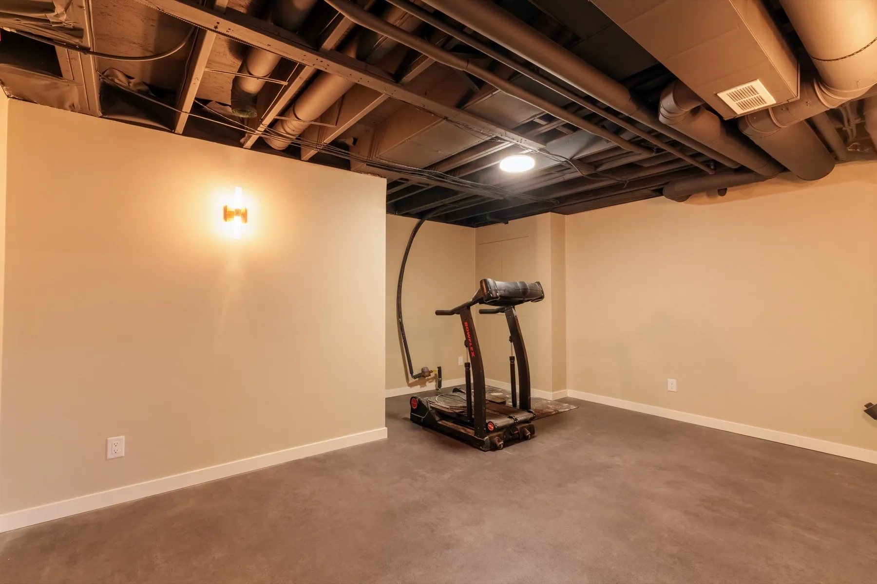 The gym area from the other side, a wall sconce over the training space