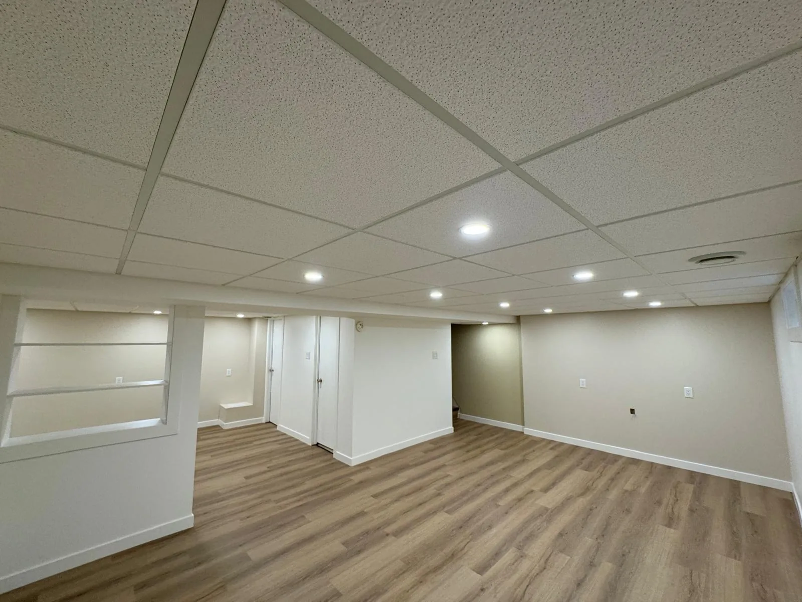 The room from the stair, suspended ceiling tiles and pot lights throughout