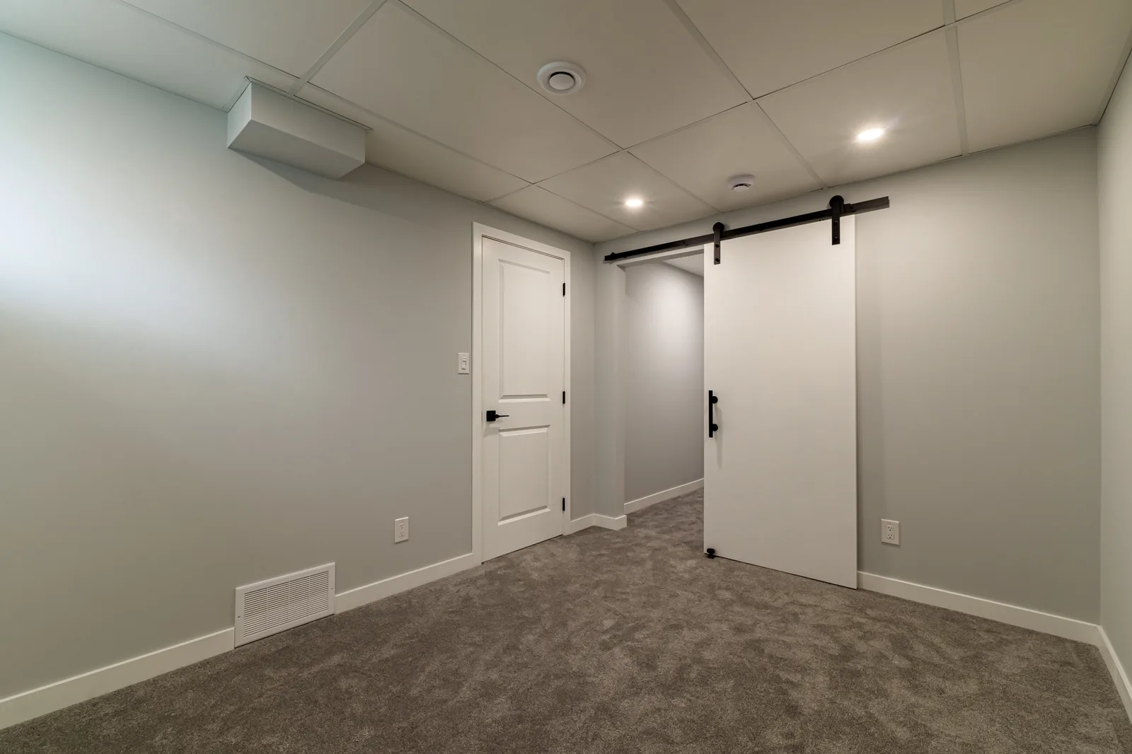 Barn door on the basement hall, rec room opening out beyond it