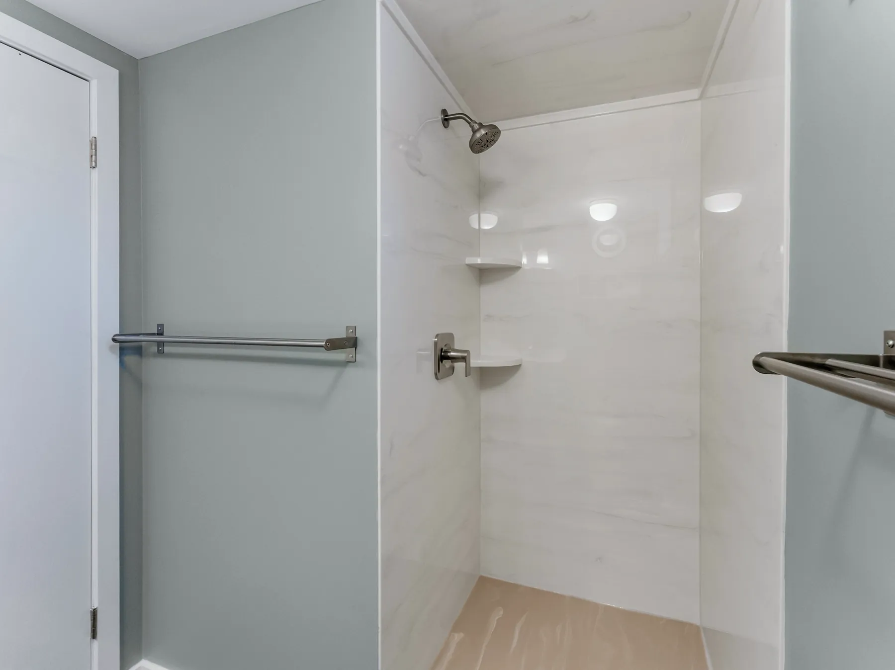 Low-threshold shower with tiled surround, corner shelves and grab bars