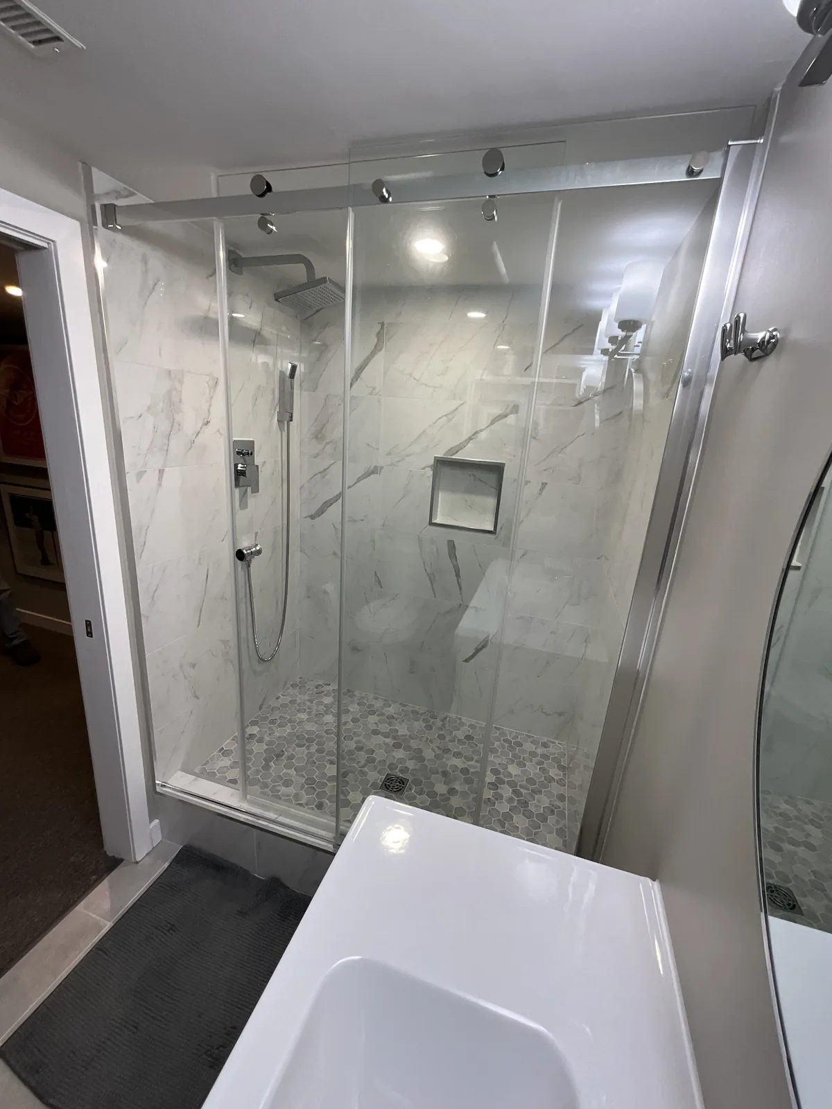 The tiled shower wall, rain head and hand shower above the bench
