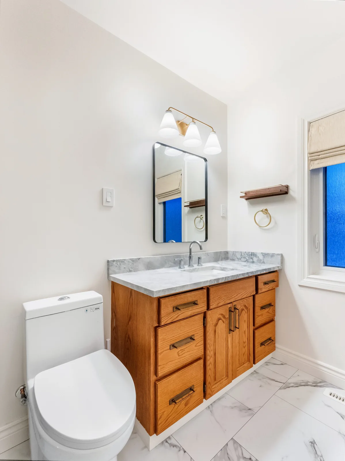 Black-framed mirror over the vanity, toilet alongside under the window