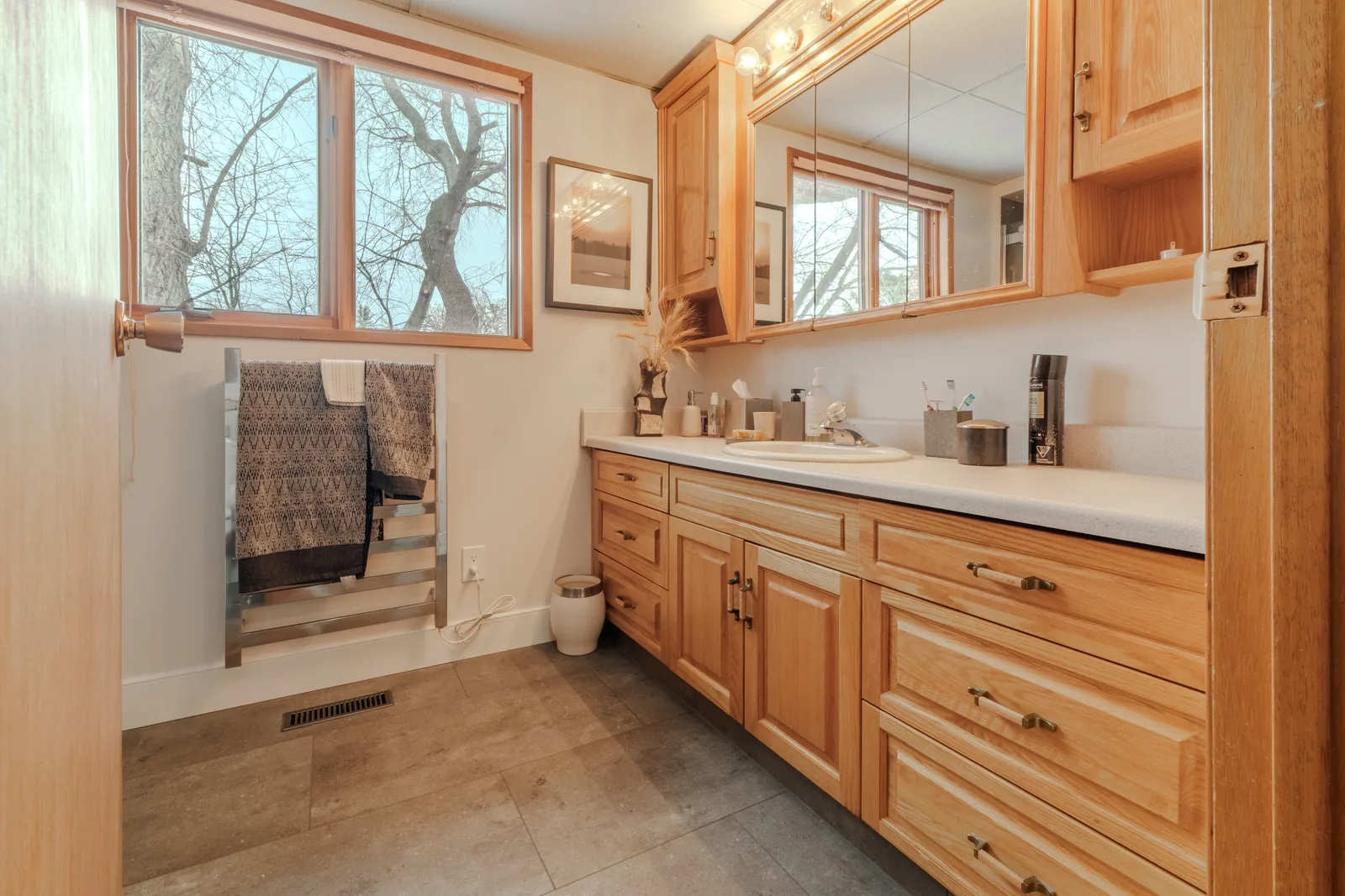 Long maple vanity run with twin mirrors, towels hung beside the shower