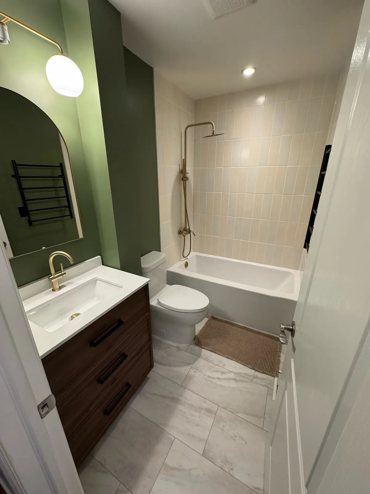 The room from the door, black towel ladder beside the tub