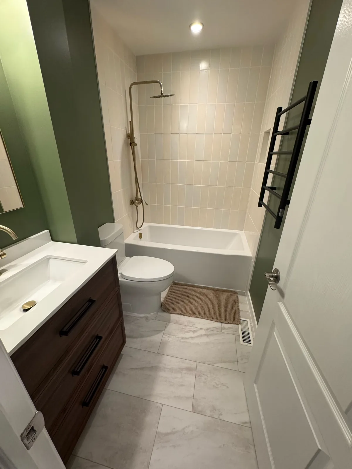 Brass rain shower over the tub, cream square tile running up the wall