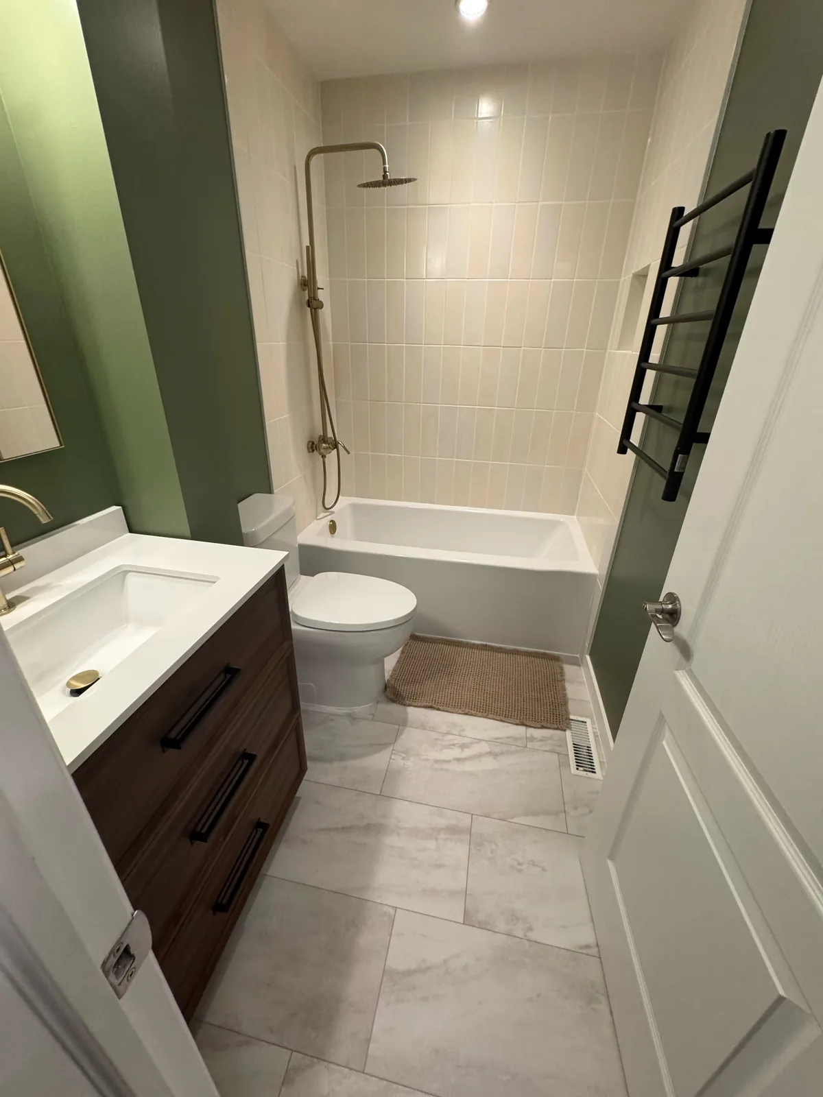 Vanity, toilet and tub in one view, marble-look tile underfoot