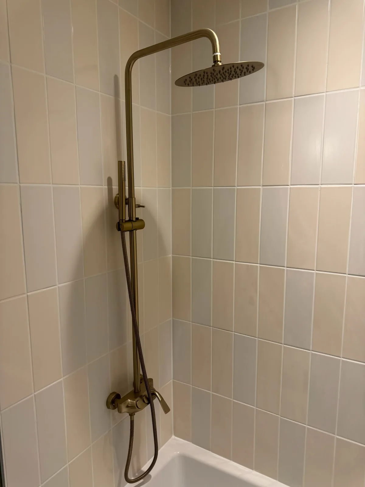 Brass rain head and hand shower against the square tile