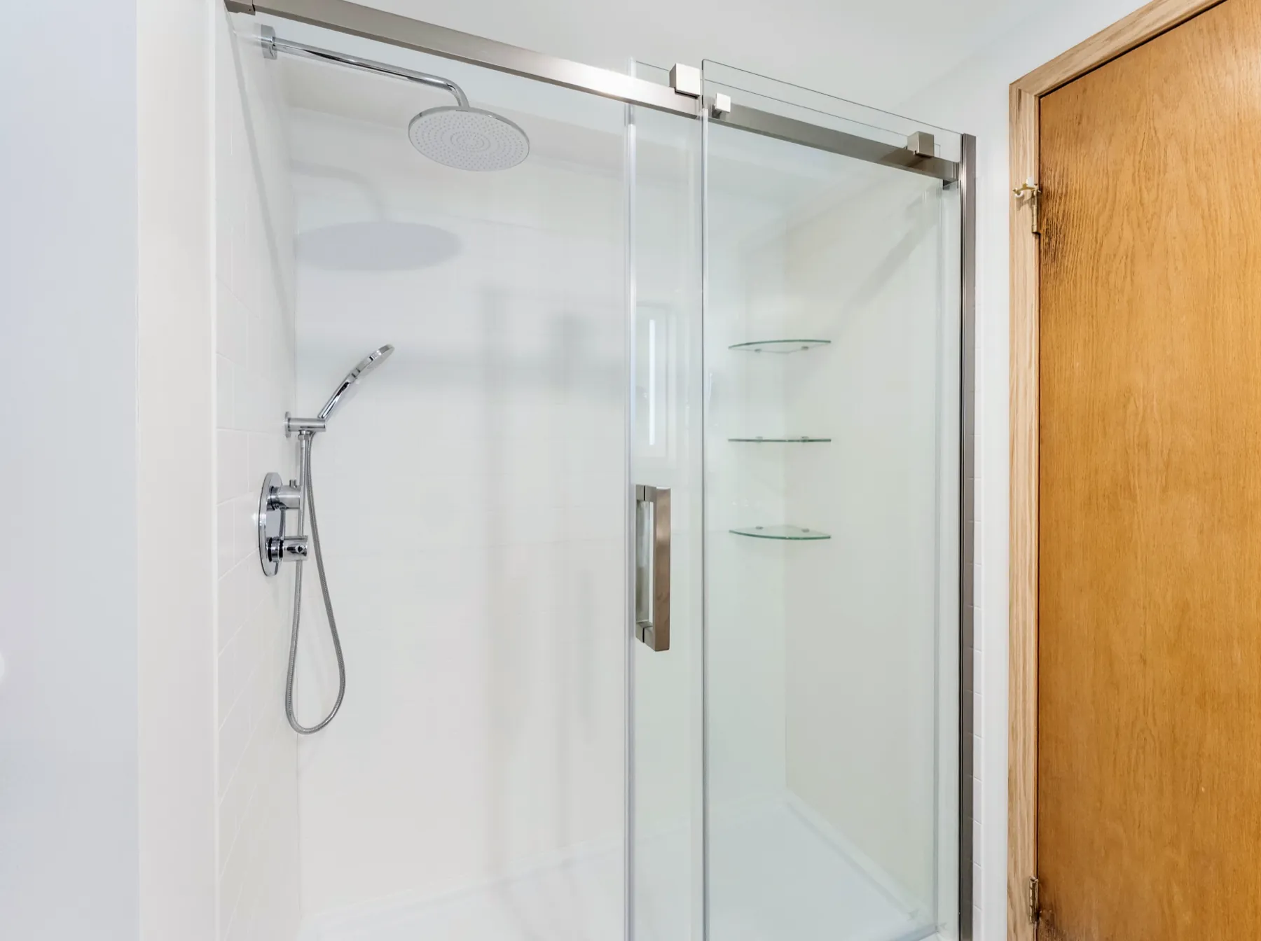 Sliding glass shower with a rain head and a wall-mounted handset