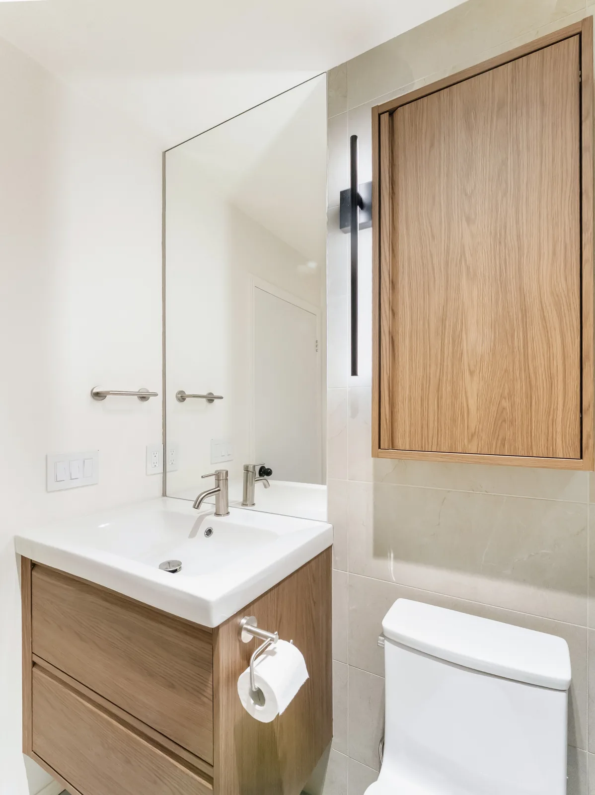 Oak wall cabinet over the toilet, vanity and mirror to the left