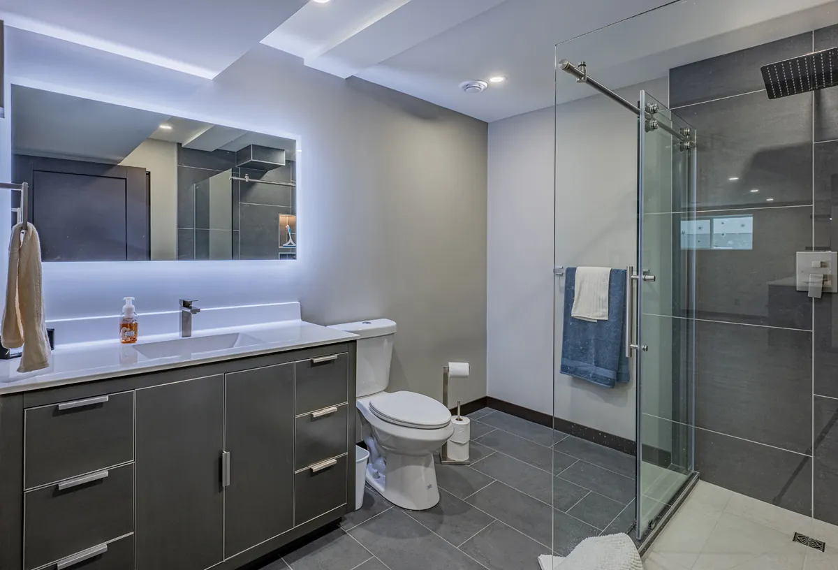 Basement bathroom with a backlit mirror and a glass shower
