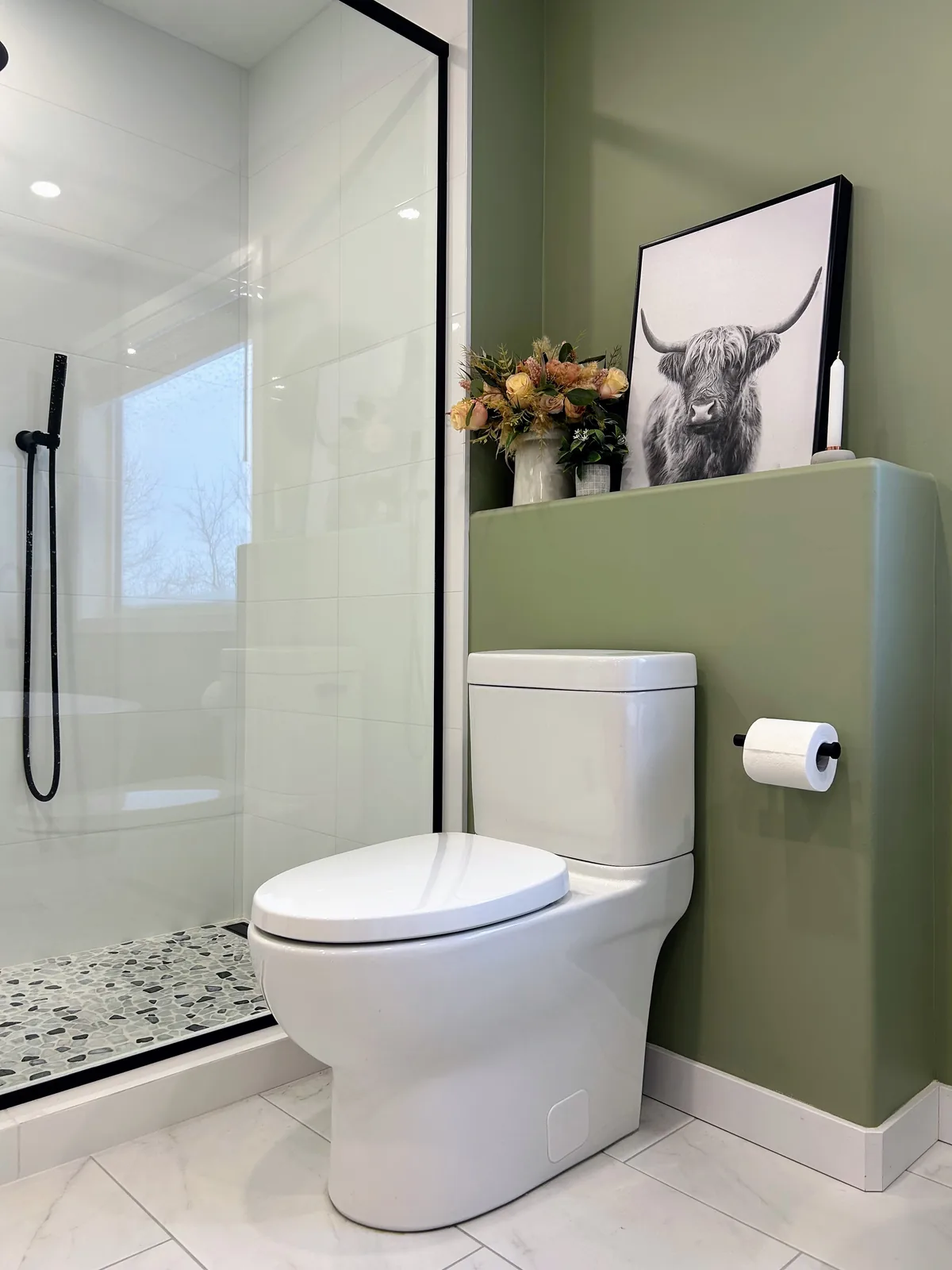 Toilet set behind a half-height partition, olive wall carried above the tile