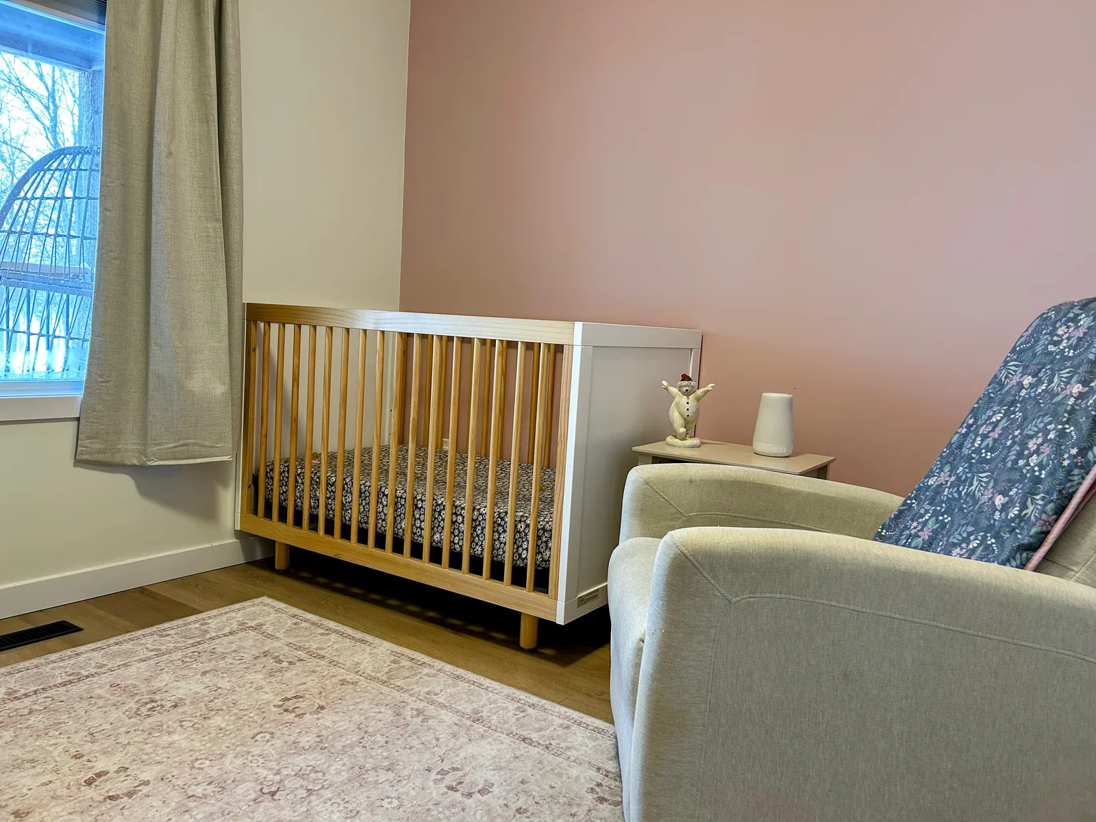 Nursery finished in the same project, oak crib against a soft pink wall