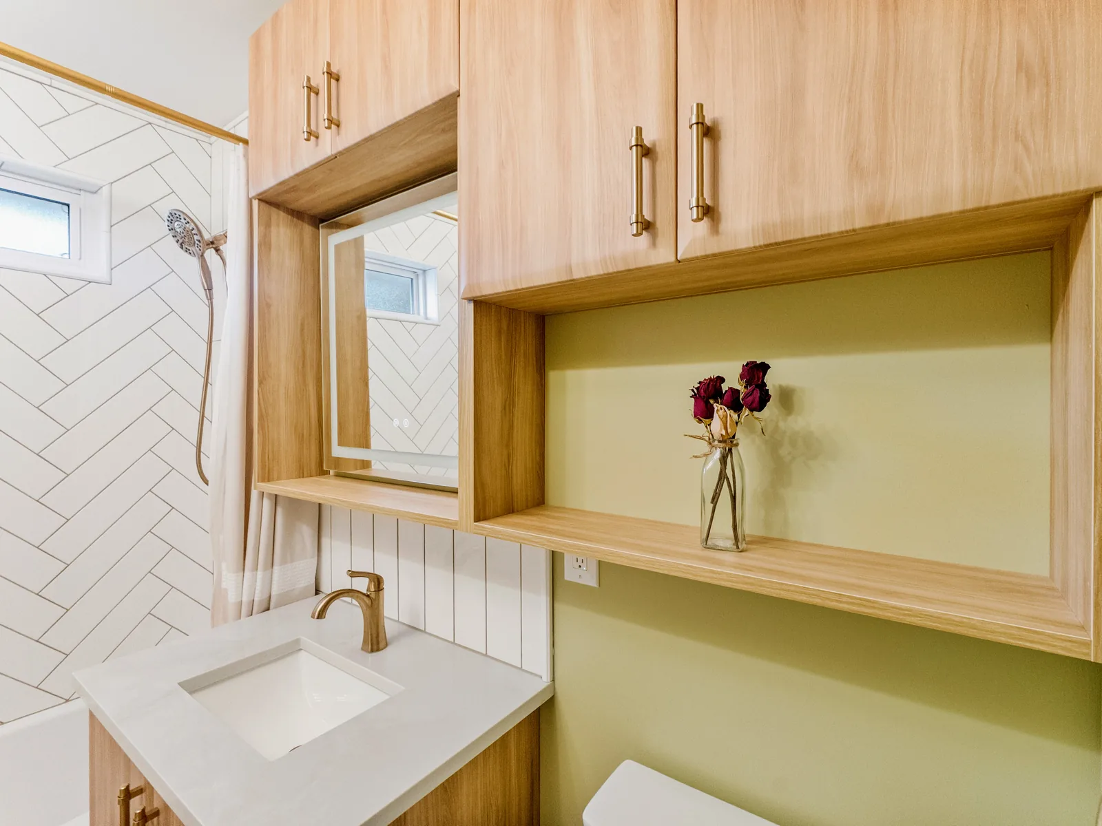 The room from the tub end — vanity, mirror and towel ring in brass