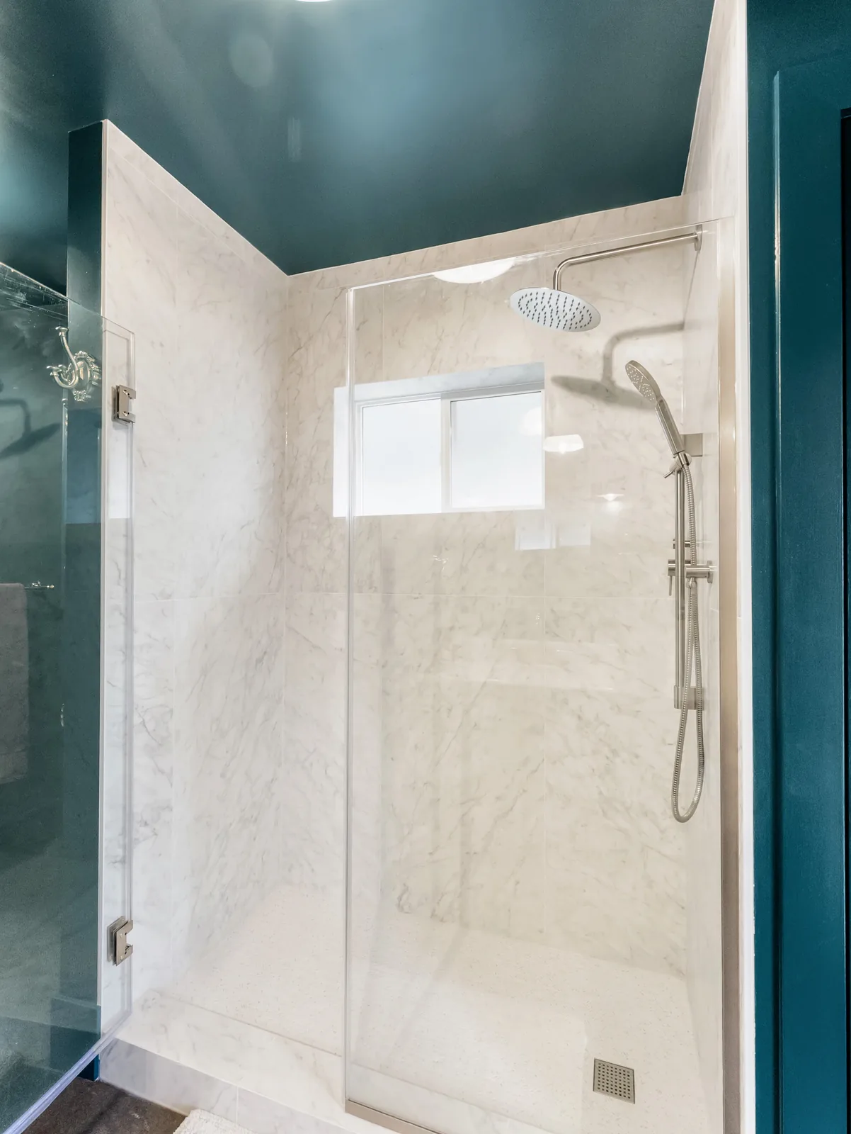 Inside the shower — marble-look slab tile, chrome rail and a recessed window