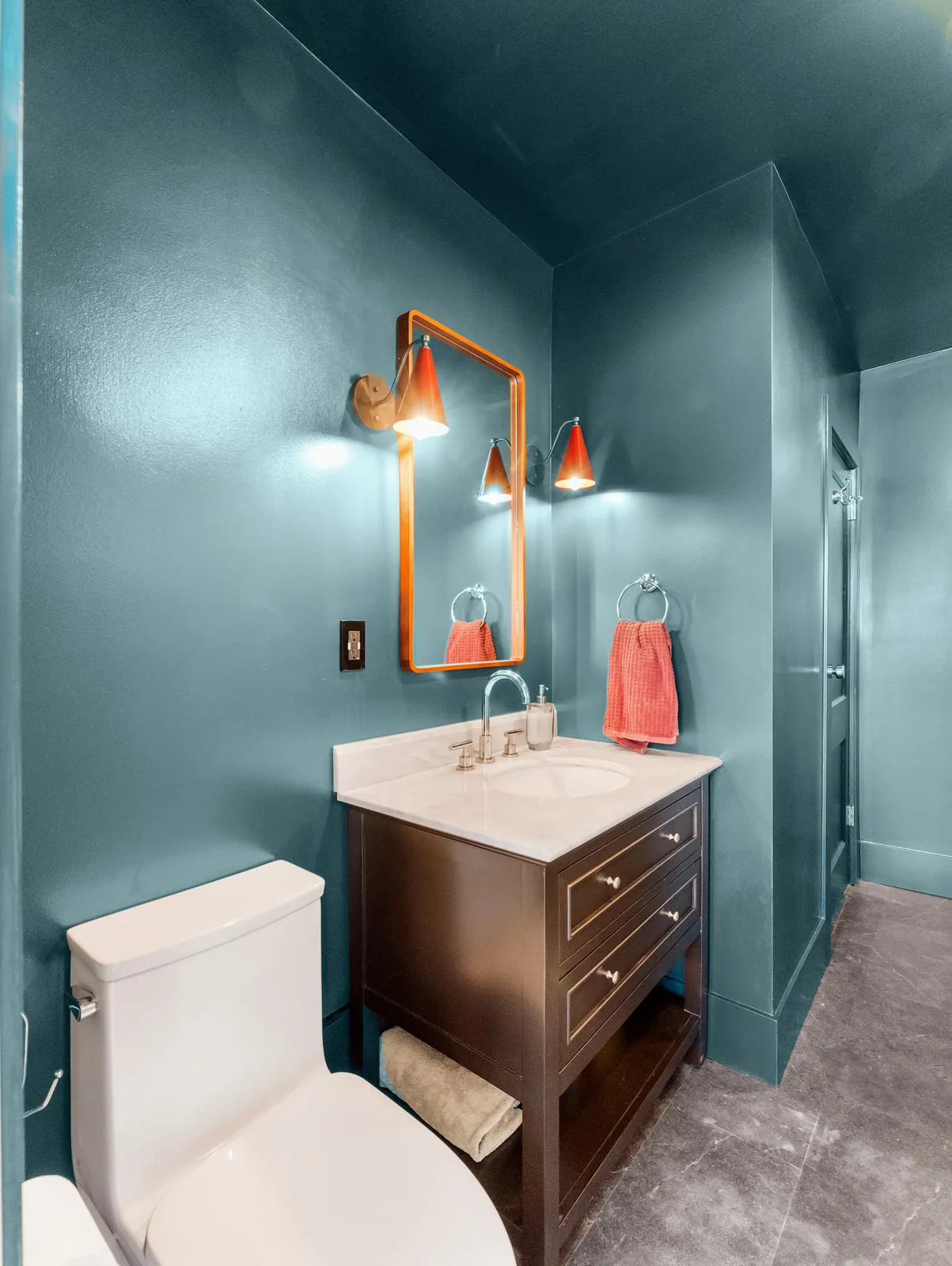 The vanity run with the toilet alongside, teal carried across every wall