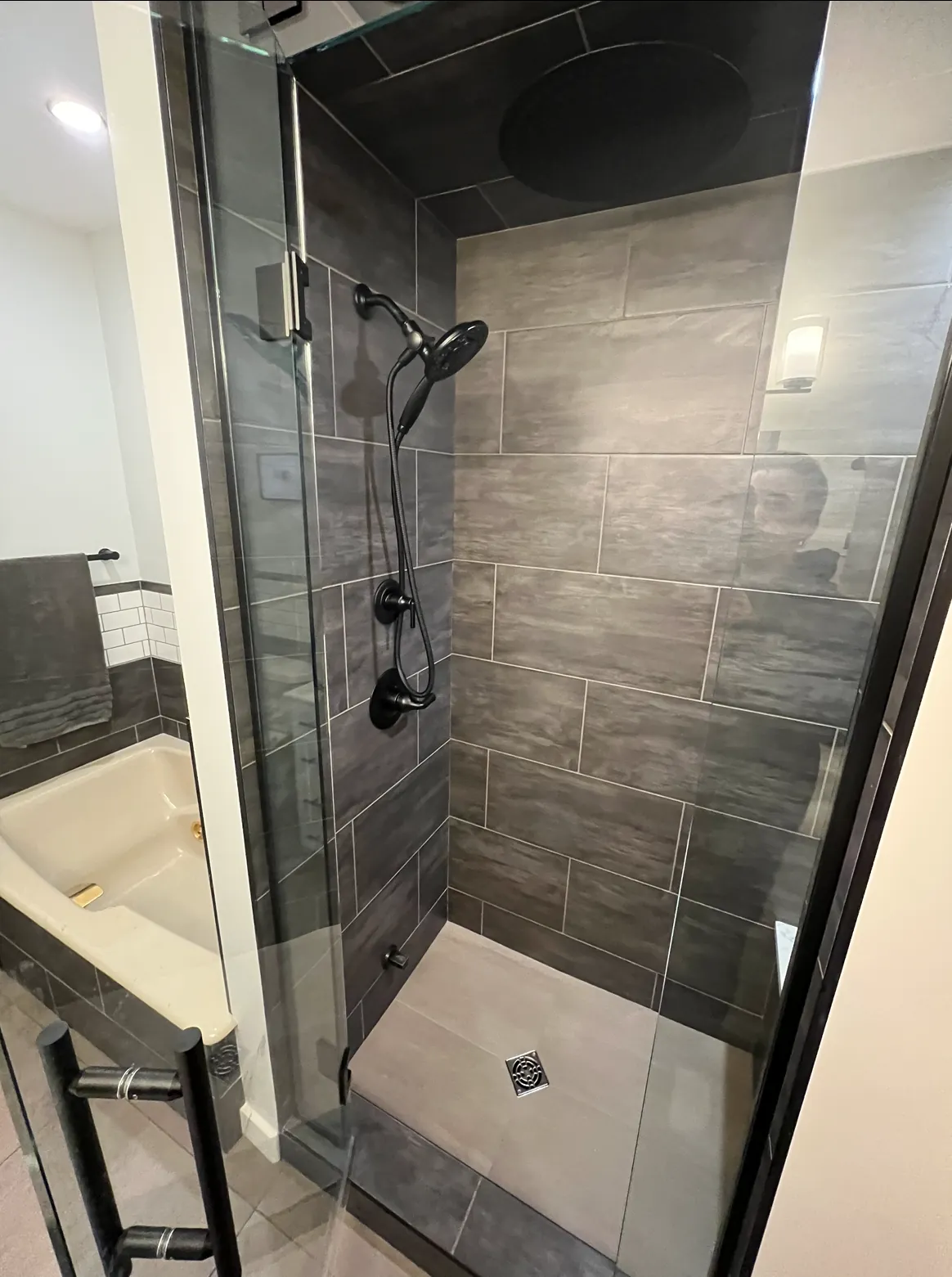 Inside a custom steam shower, dark porcelain tile with a rain head