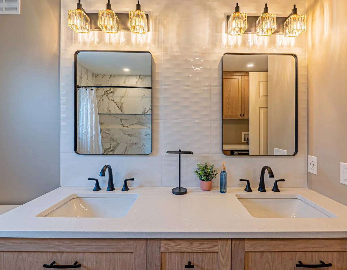 Twin basins in white quartz in the main bathroom, black taps against the oak drawers