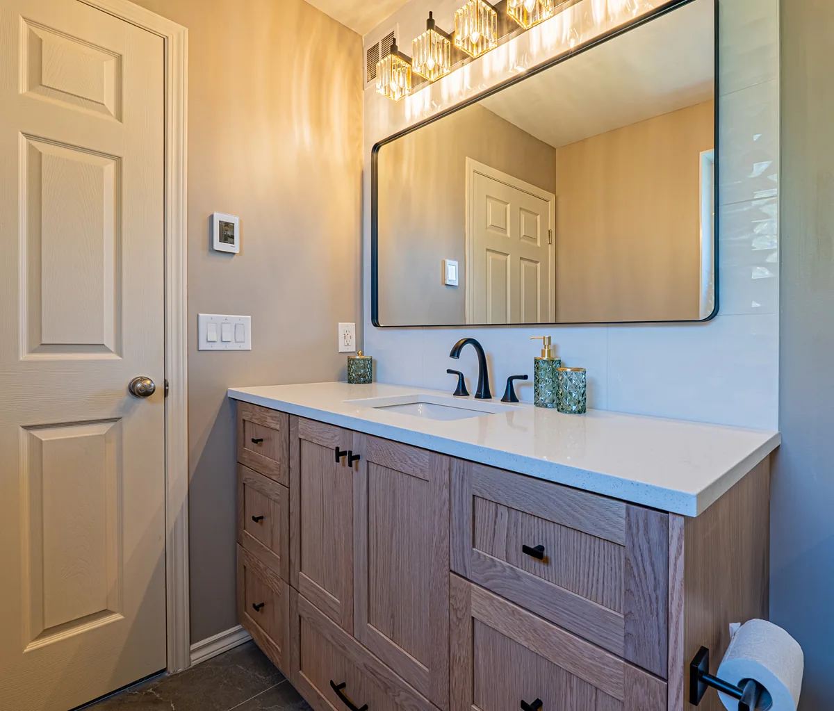 The ensuite vanity and mirror from the doorway, oak against the pale walls