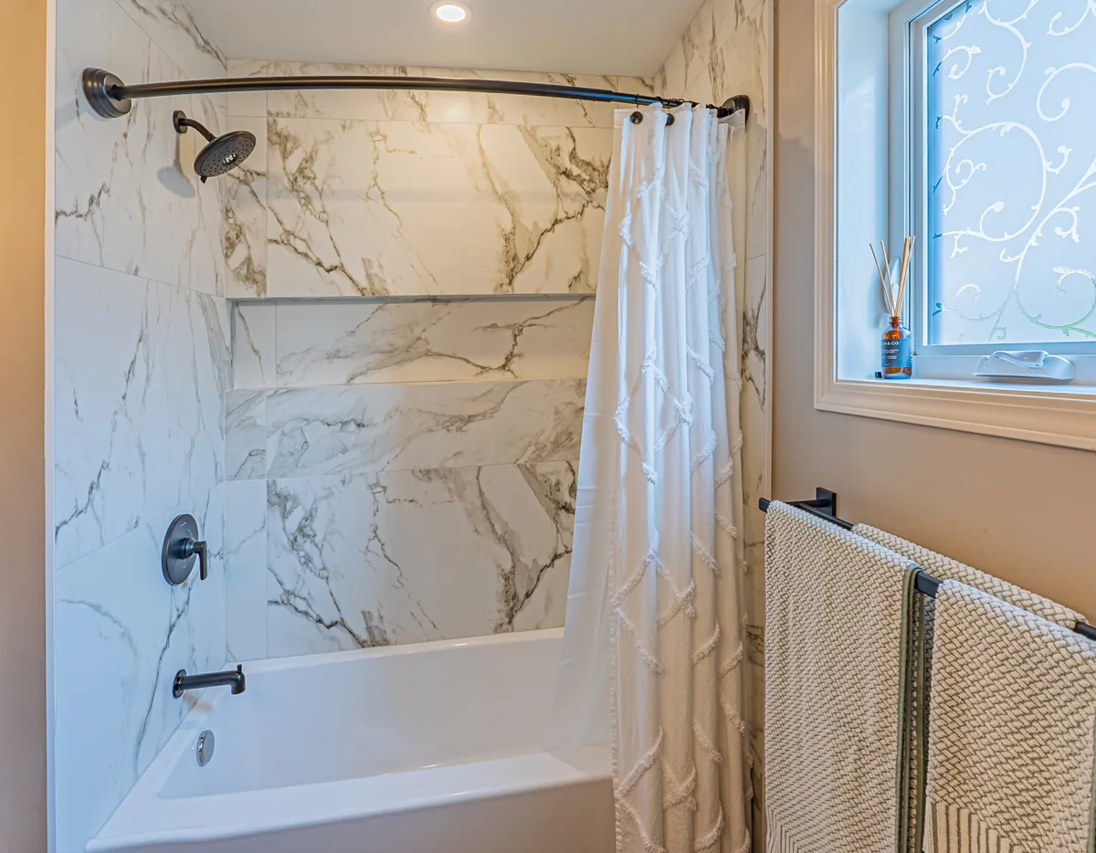 The tub under the window, curtain rail run across the tiled surround