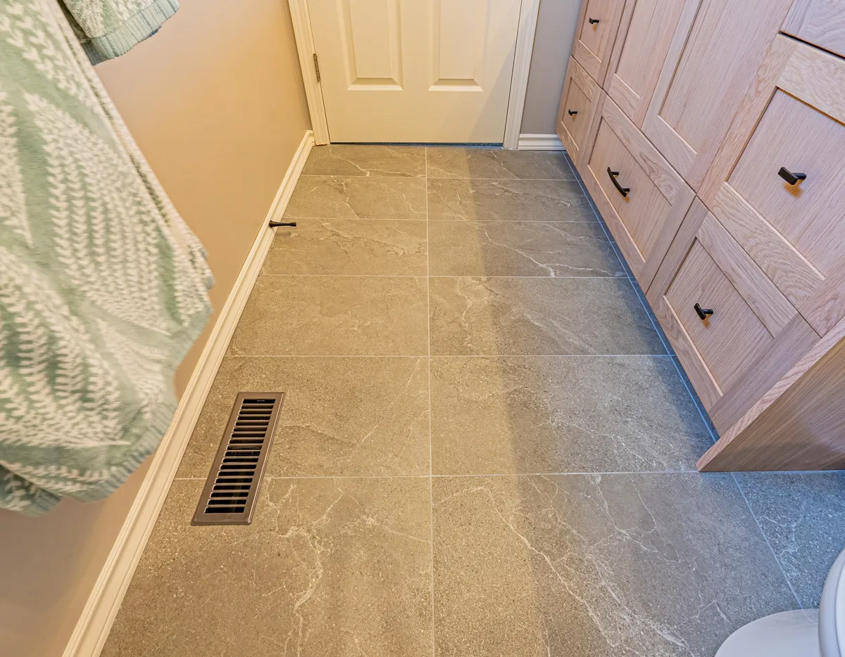 Large-format grey tile running the length of the ensuite past the vanity drawers