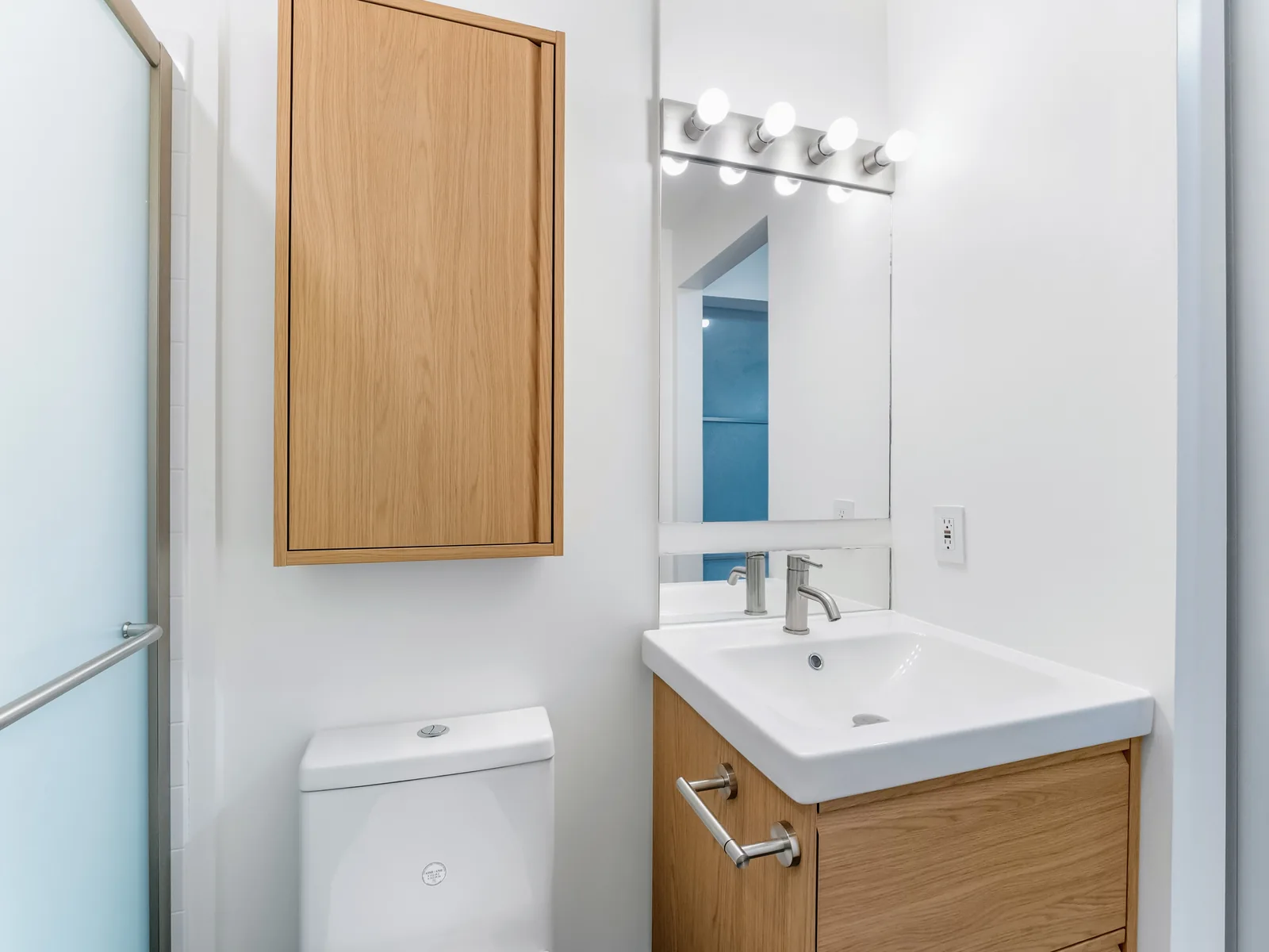 Oak mirrored wall cabinet over the toilet, bar light above the vanity mirror