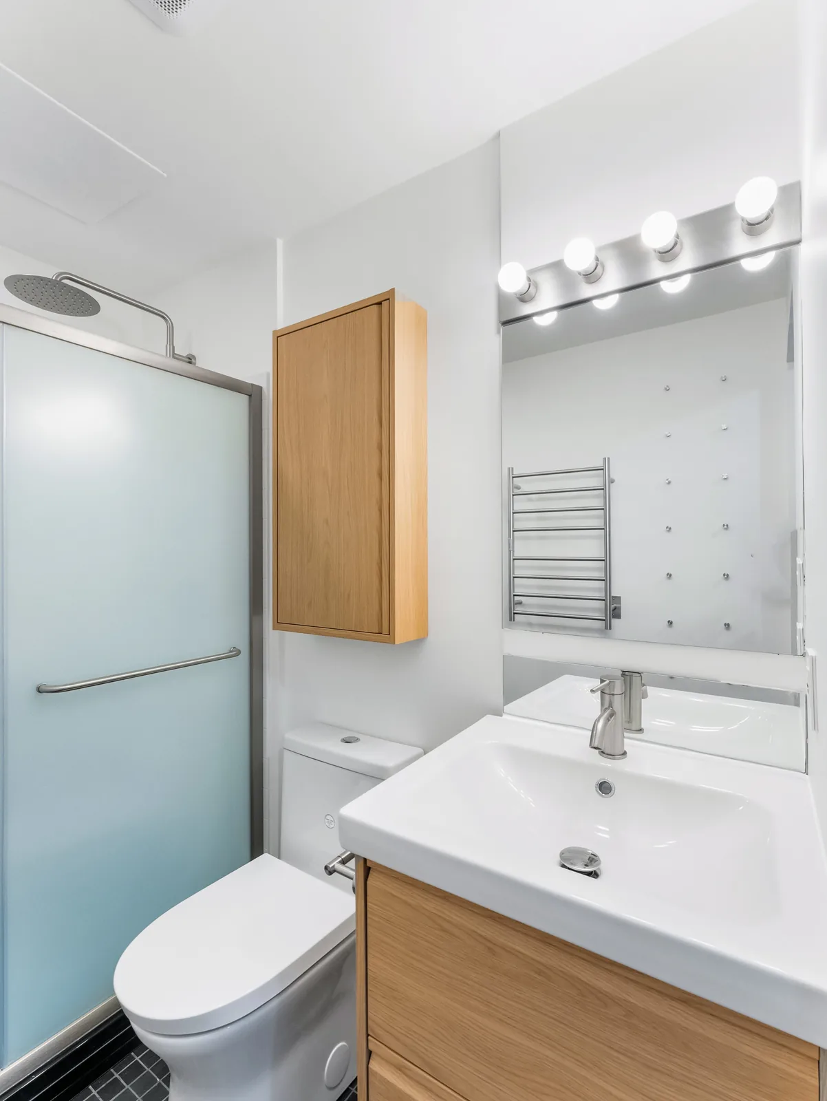 The room end to end, vanity and toilet with the shower at the far wall