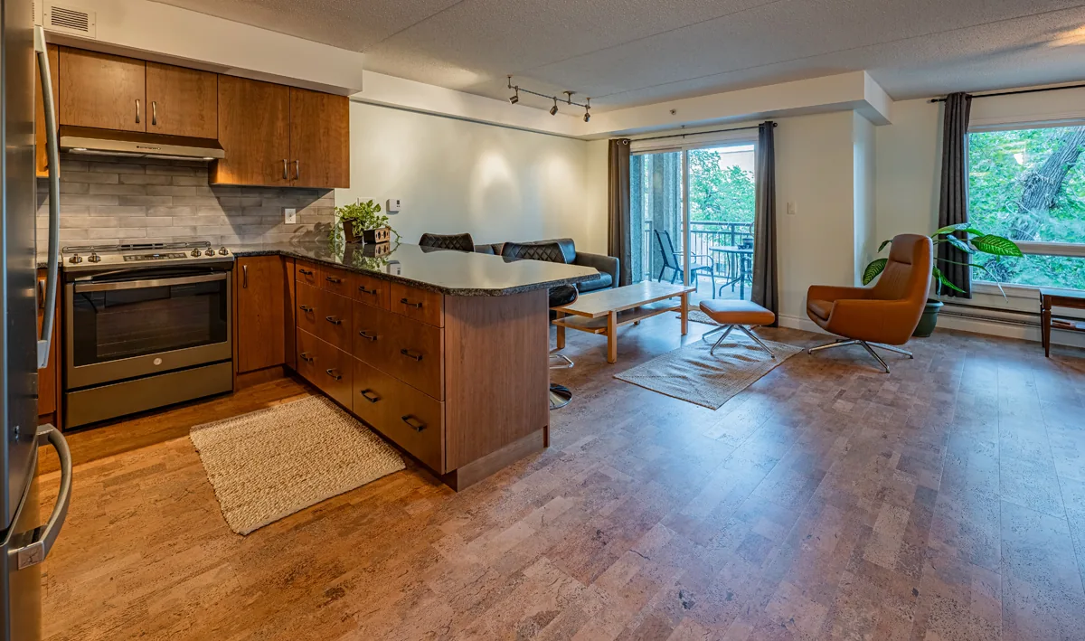 Condo kitchen open to the living room, cork plank flooring carried through to the balcony doors