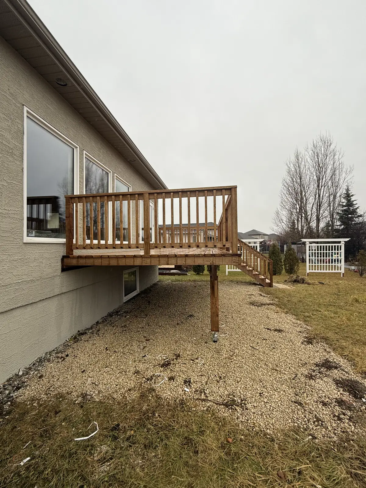 The deck along the back wall, set on cedar posts above the gravel