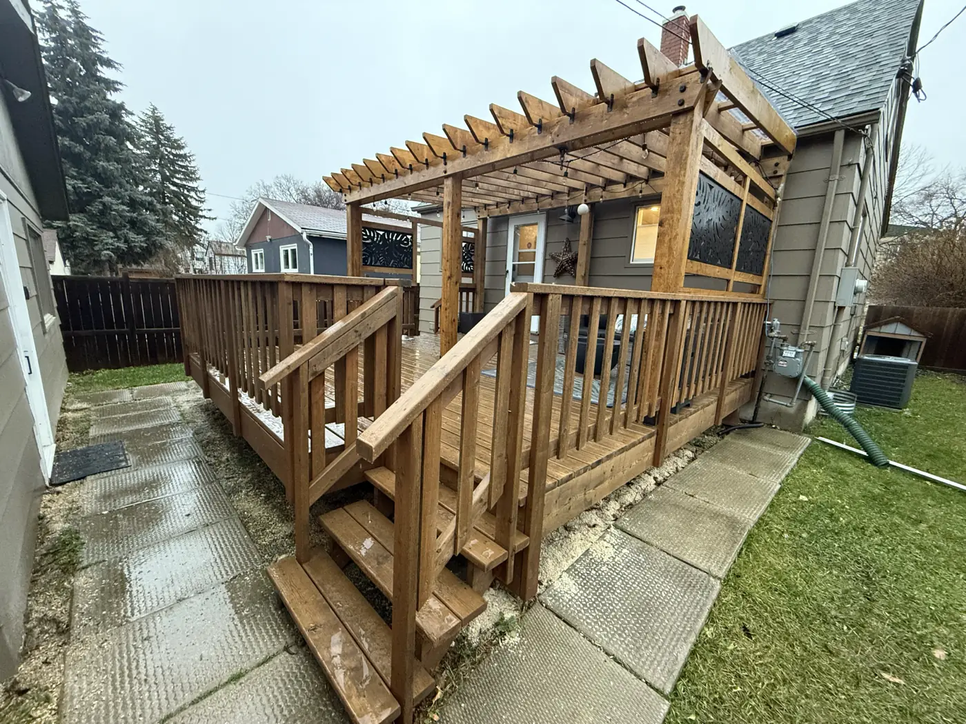 The deck and its stair from the yard, railings and screens in profile