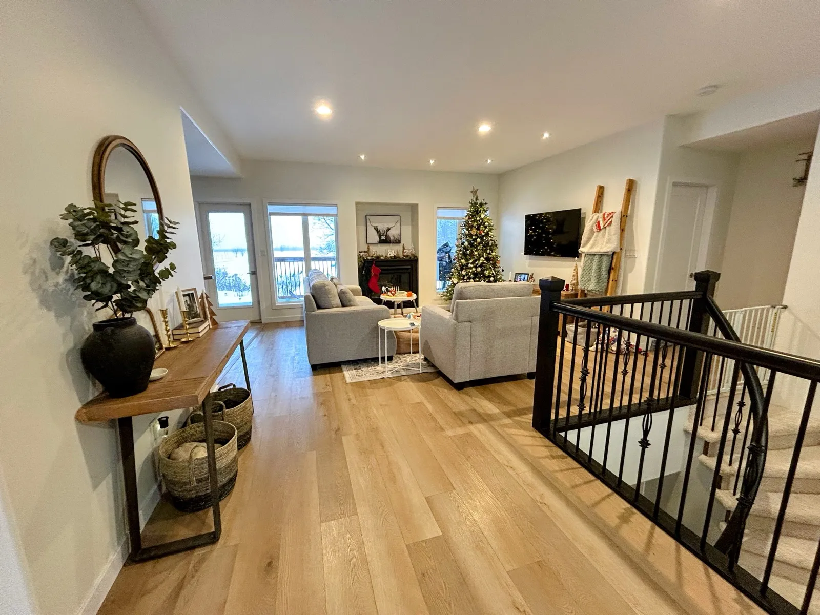 New wide-plank flooring through the main living area, the black stair railing at the top of the stairs