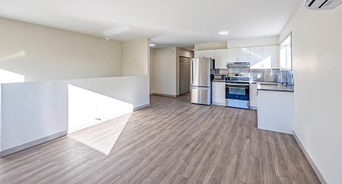 Open living area looking through to a new kitchen, vinyl plank throughout