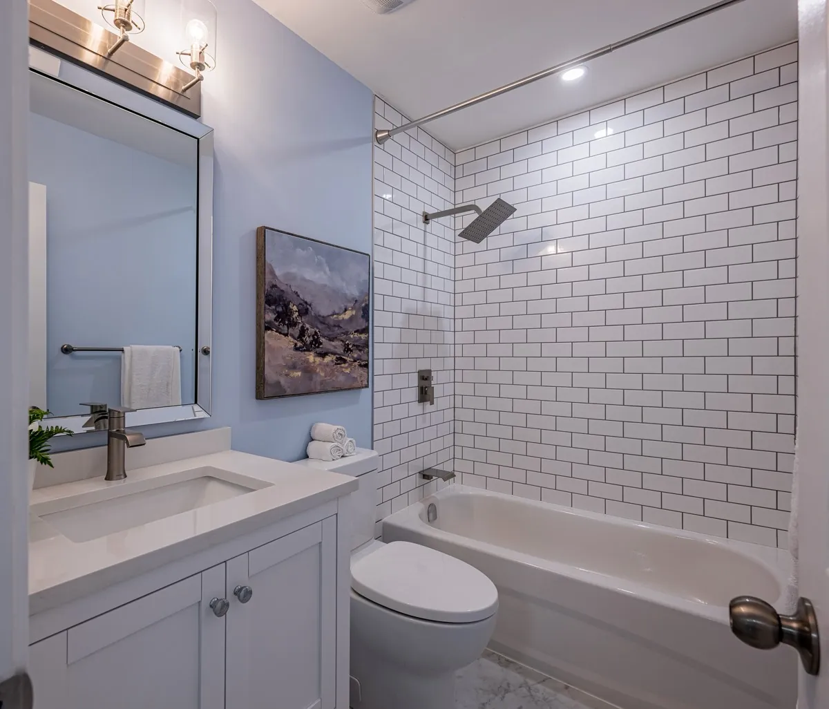 Bathroom with a subway-tiled tub surround and a framed mirror