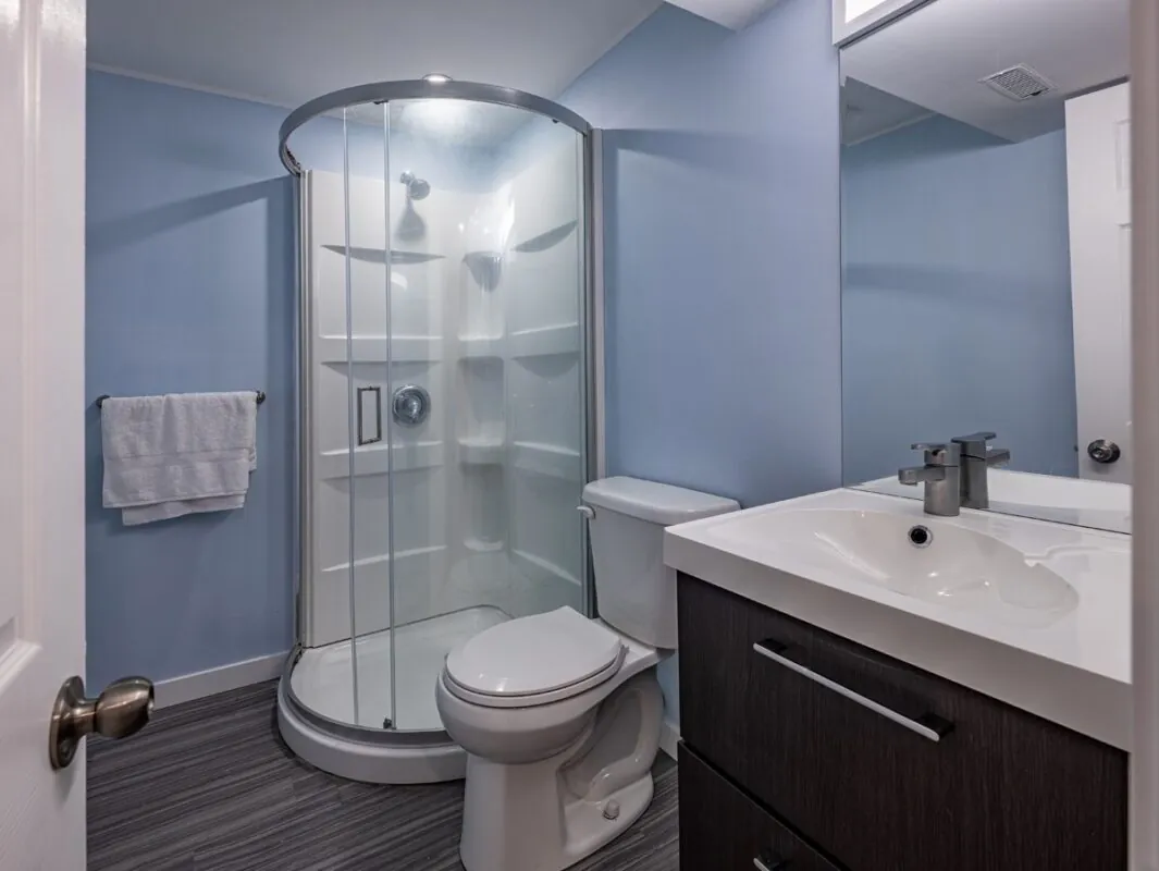 Second bathroom, corner shower against a blue wall