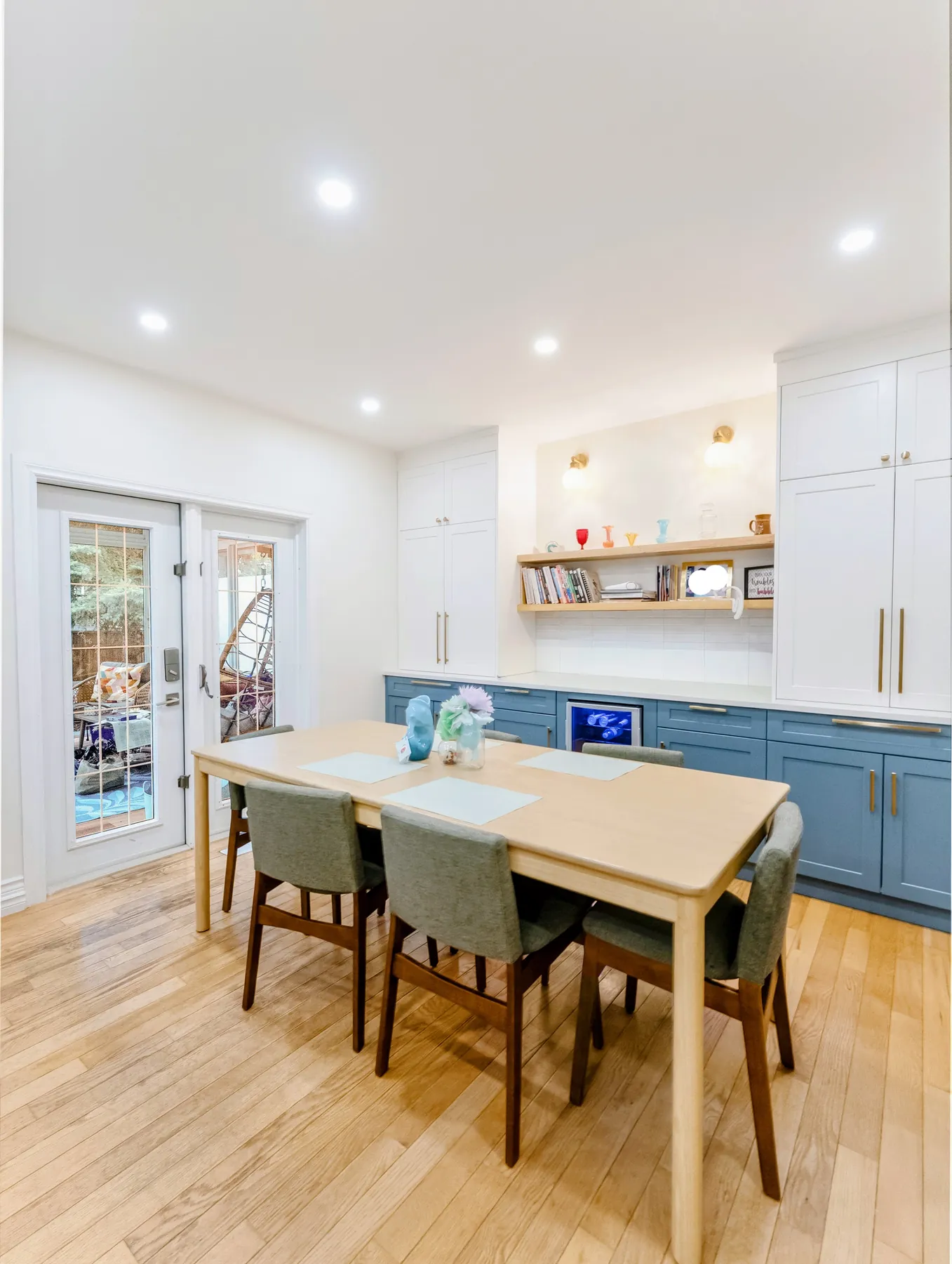 The dining table before the blue sideboard run, white uppers and an oak shelf above
