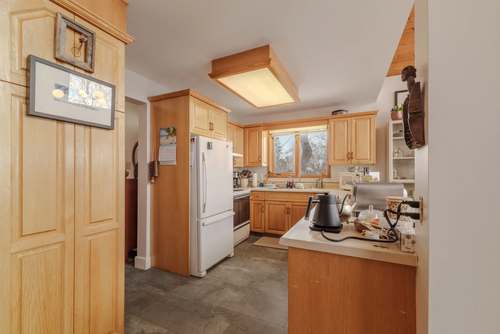 Maple kitchen with a centre island under a panelled ceiling light