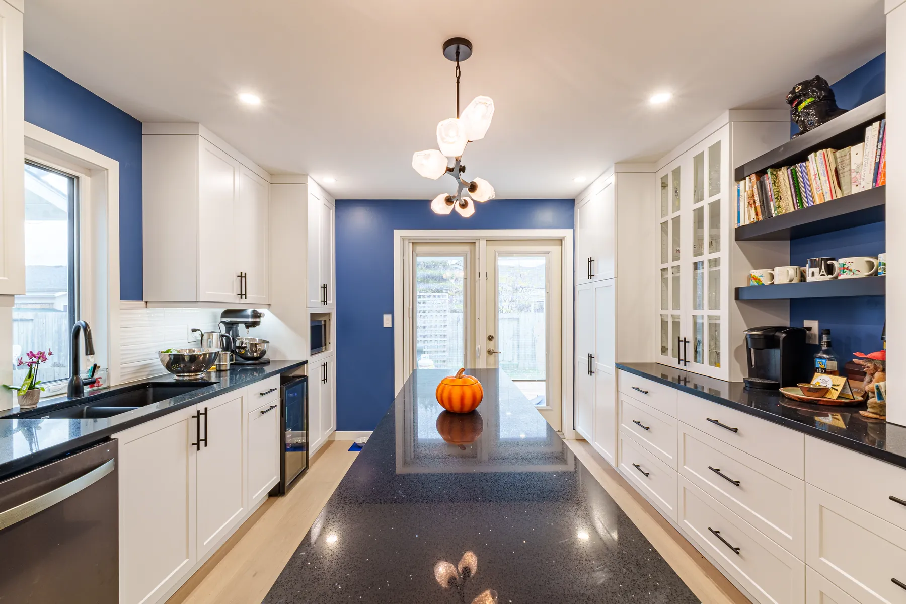 White kitchen against navy walls, with a navy island under a black speckled quartz top