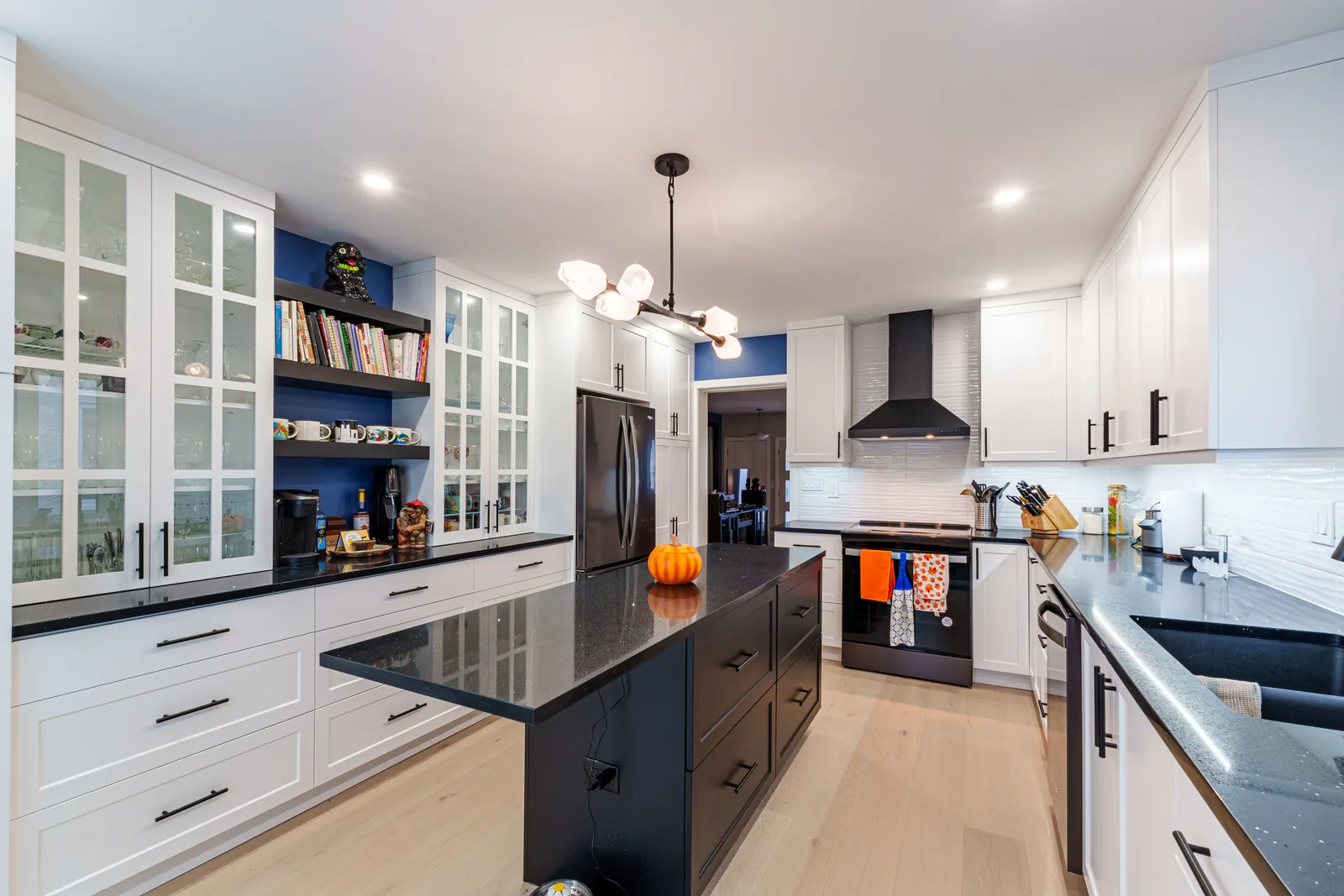 The island run under a chandelier, glass-front uppers along the wall