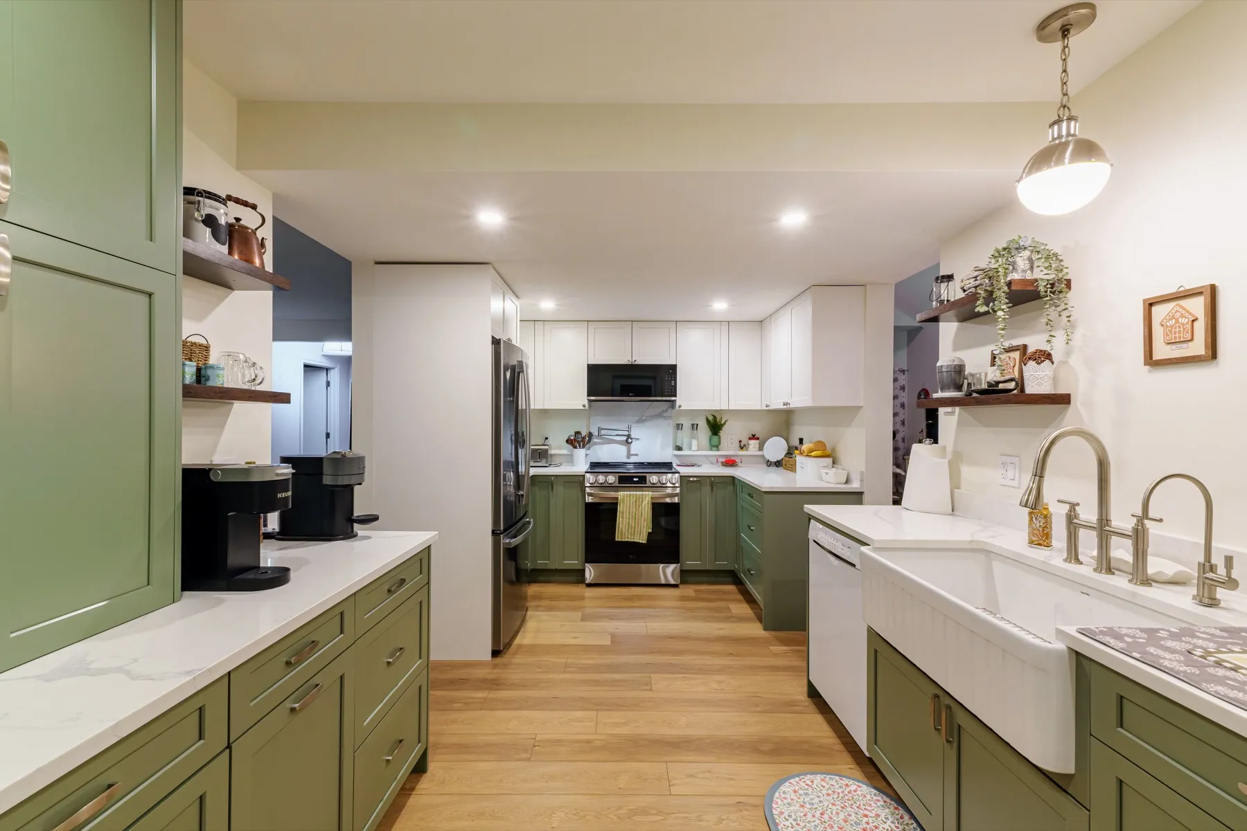Looking down the kitchen from the sink to the range, white quartz on olive shaker cabinetry