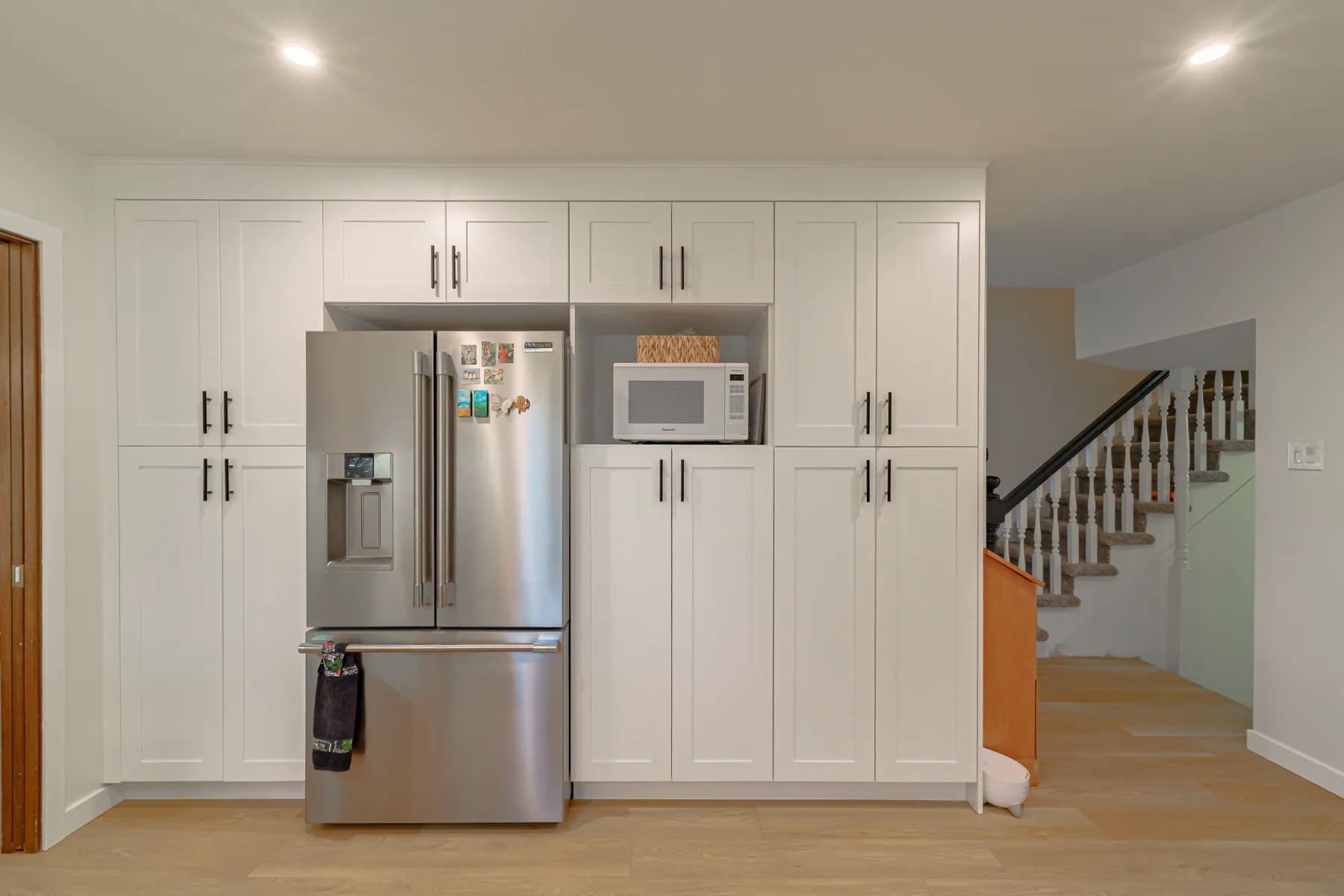 Cabinetry run beside the staircase, looking back through the kitchen