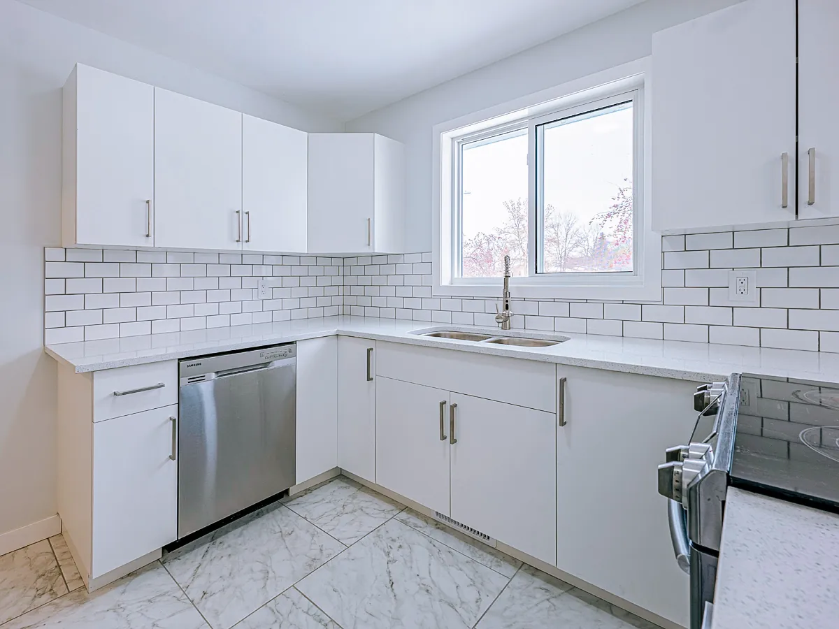 White kitchen with a subway backsplash, quartz counters and a marble-look tile floor