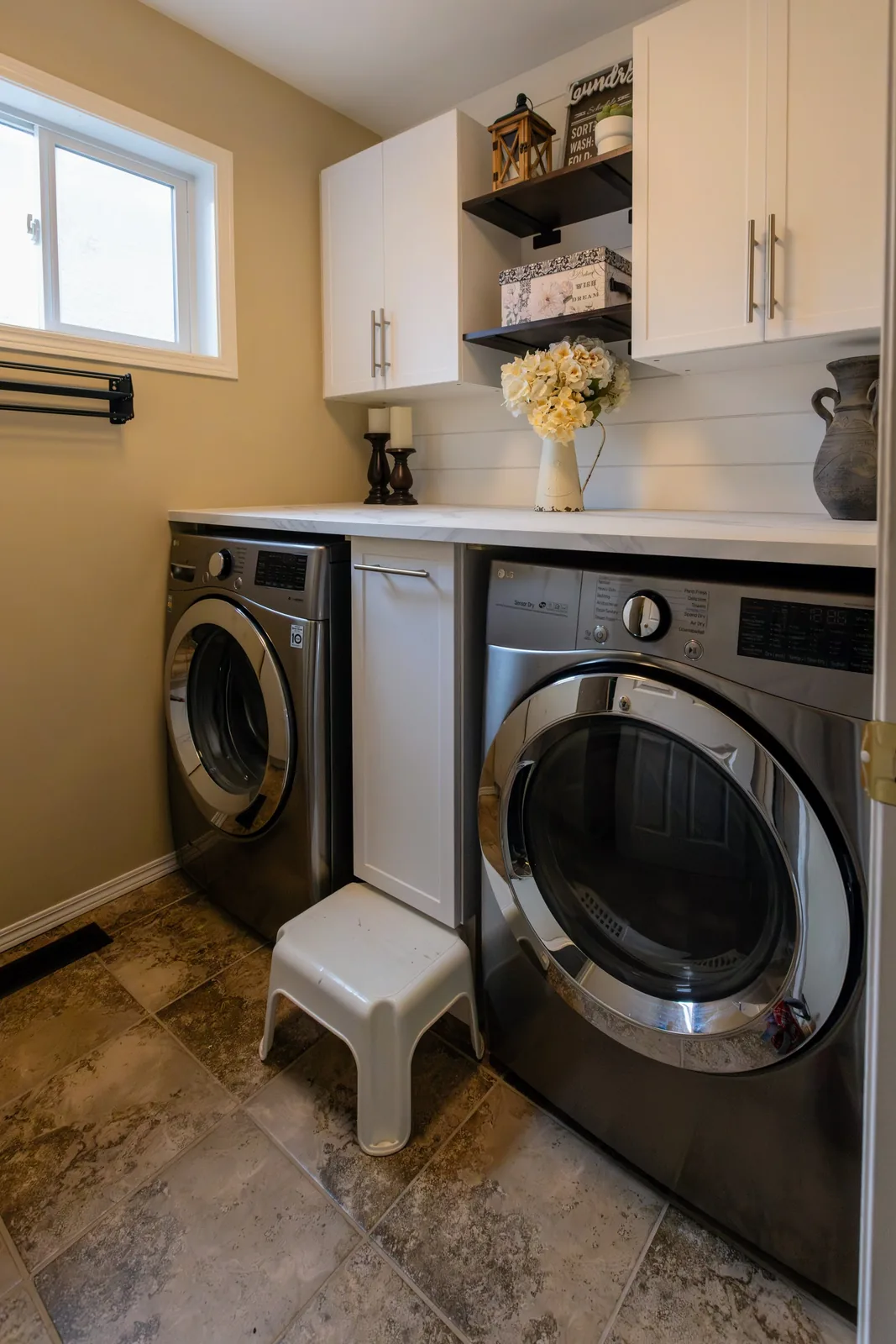 Laundry room with white shaker uppers and a marble-look counter over the washer and dryer