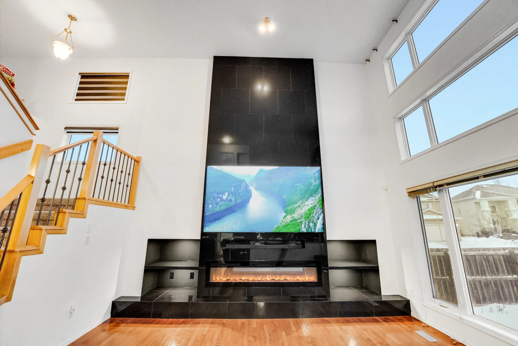 The full height of the wall, black tile from the hearth to the ceiling with the stair to one side