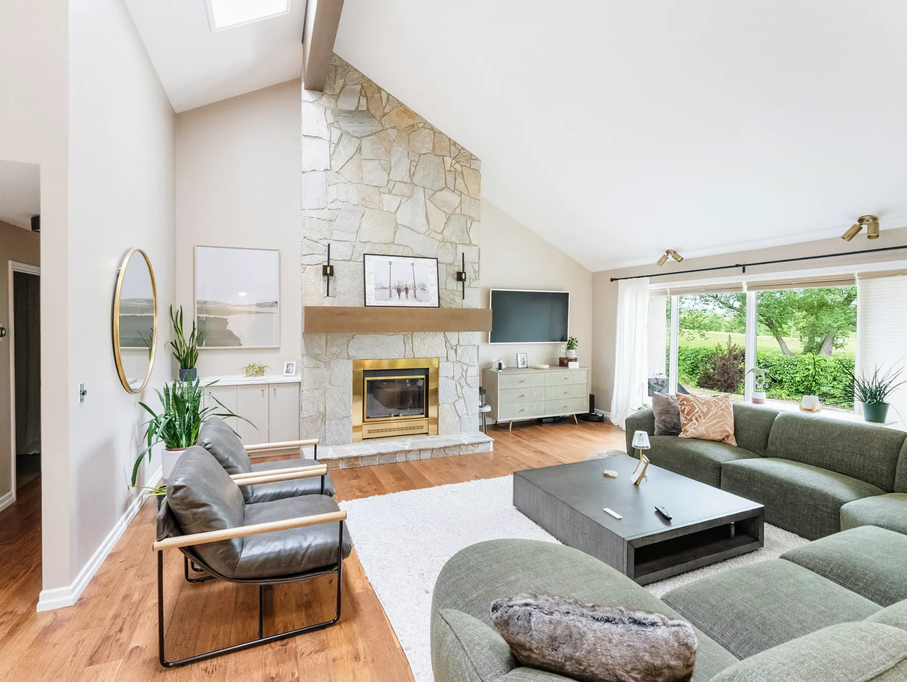 Vaulted living room with a stone fireplace and a green sectional