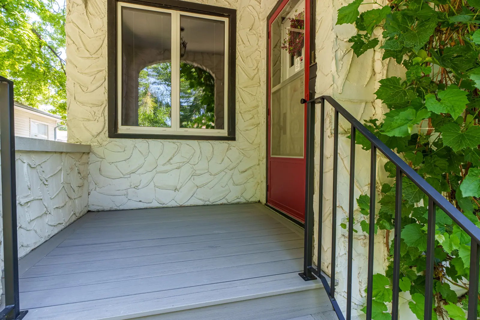 Composite front steps and landing at a red door, black metal railing either side