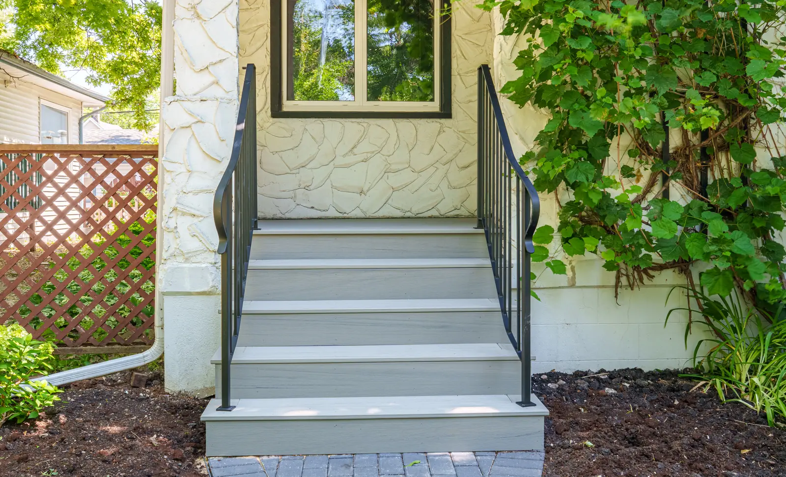 The steps head on, grey composite treads against the stucco