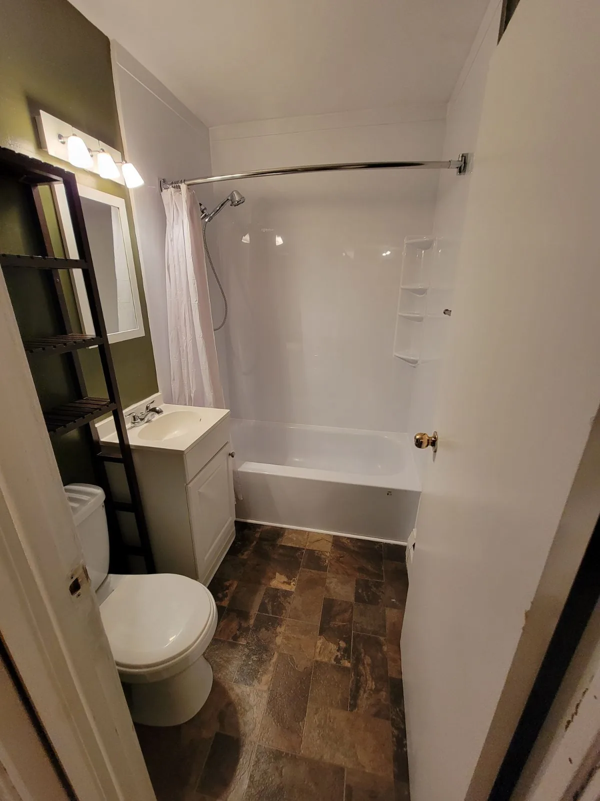 The bathroom with its new vanity, toilet and tub surround