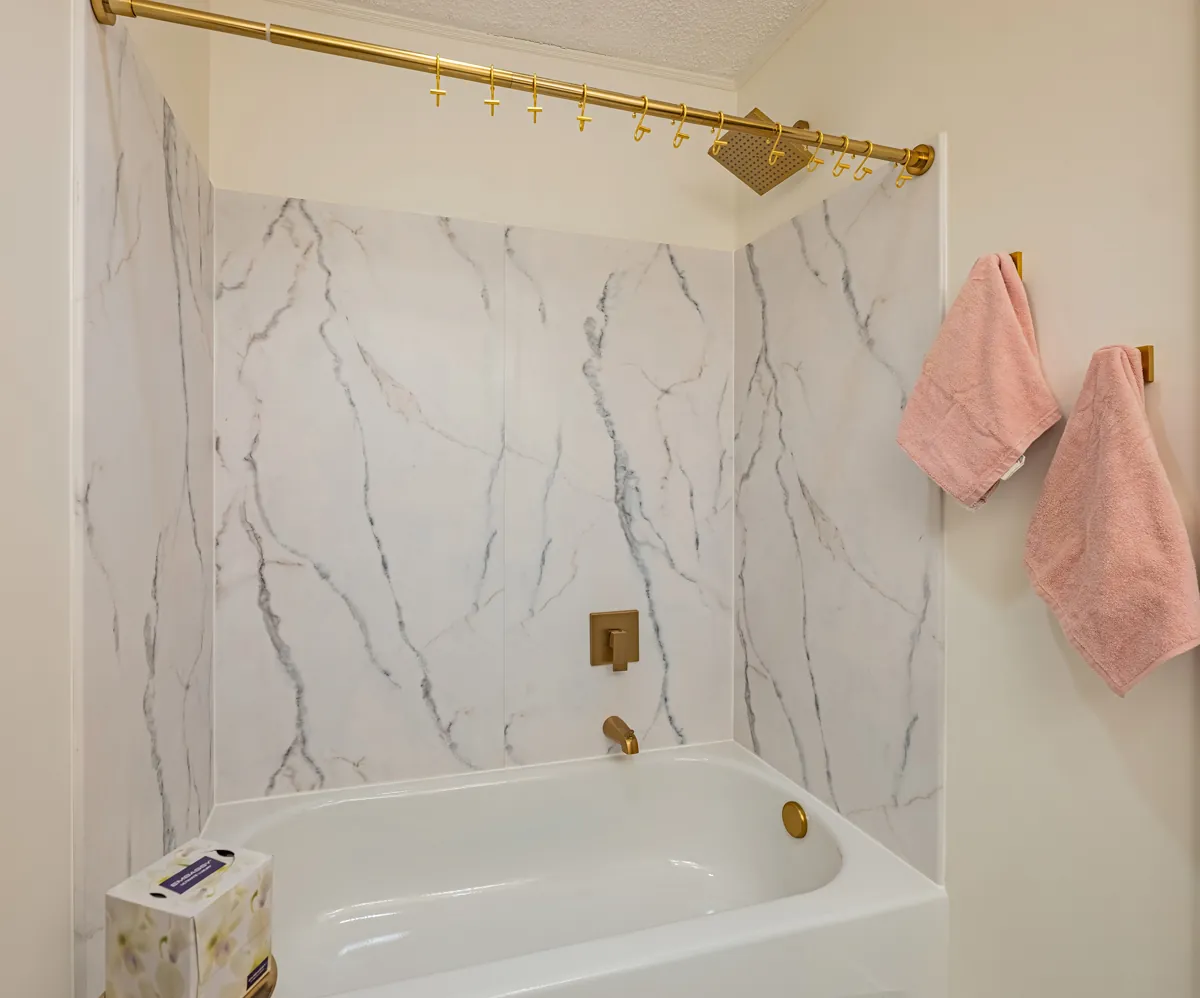 First bathroom tub-shower in marble-look tile, a gold rail and rain head