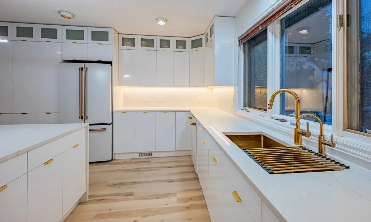 The sink run under the window, a gold sink and tap set into white quartz