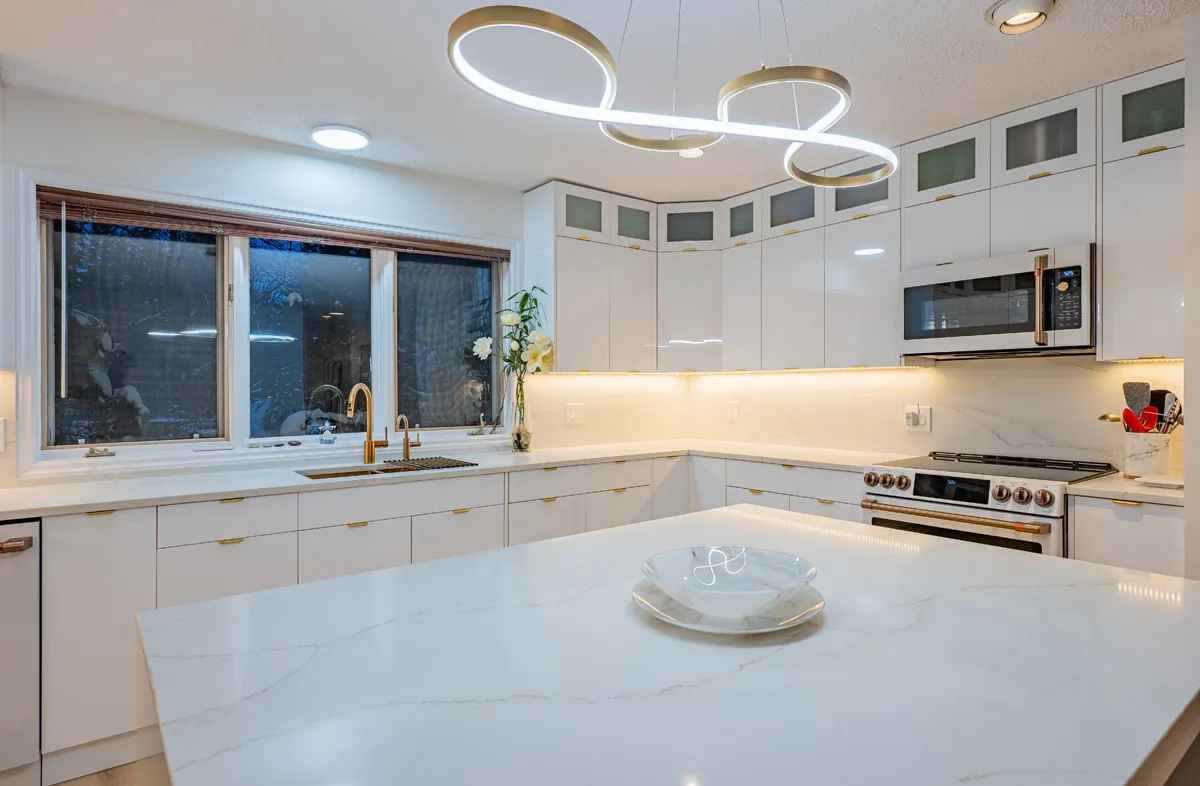 The island top under a gold ribbon pendant, the window wall beyond